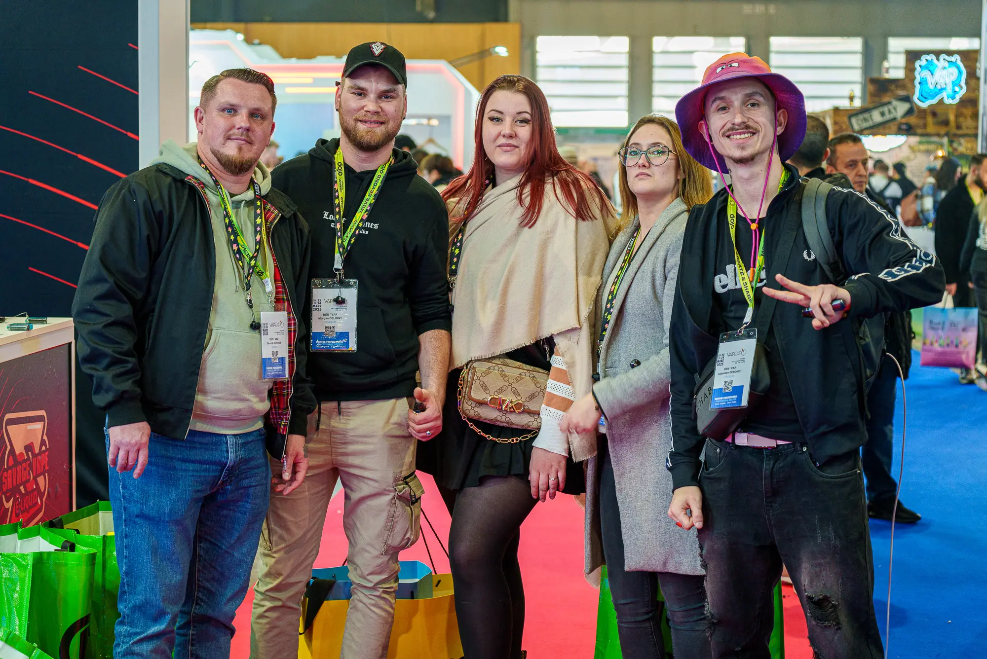 Un groupe de visiteurs portant leur badge d'accès posant dans les allées du salon Vapexpo Paris