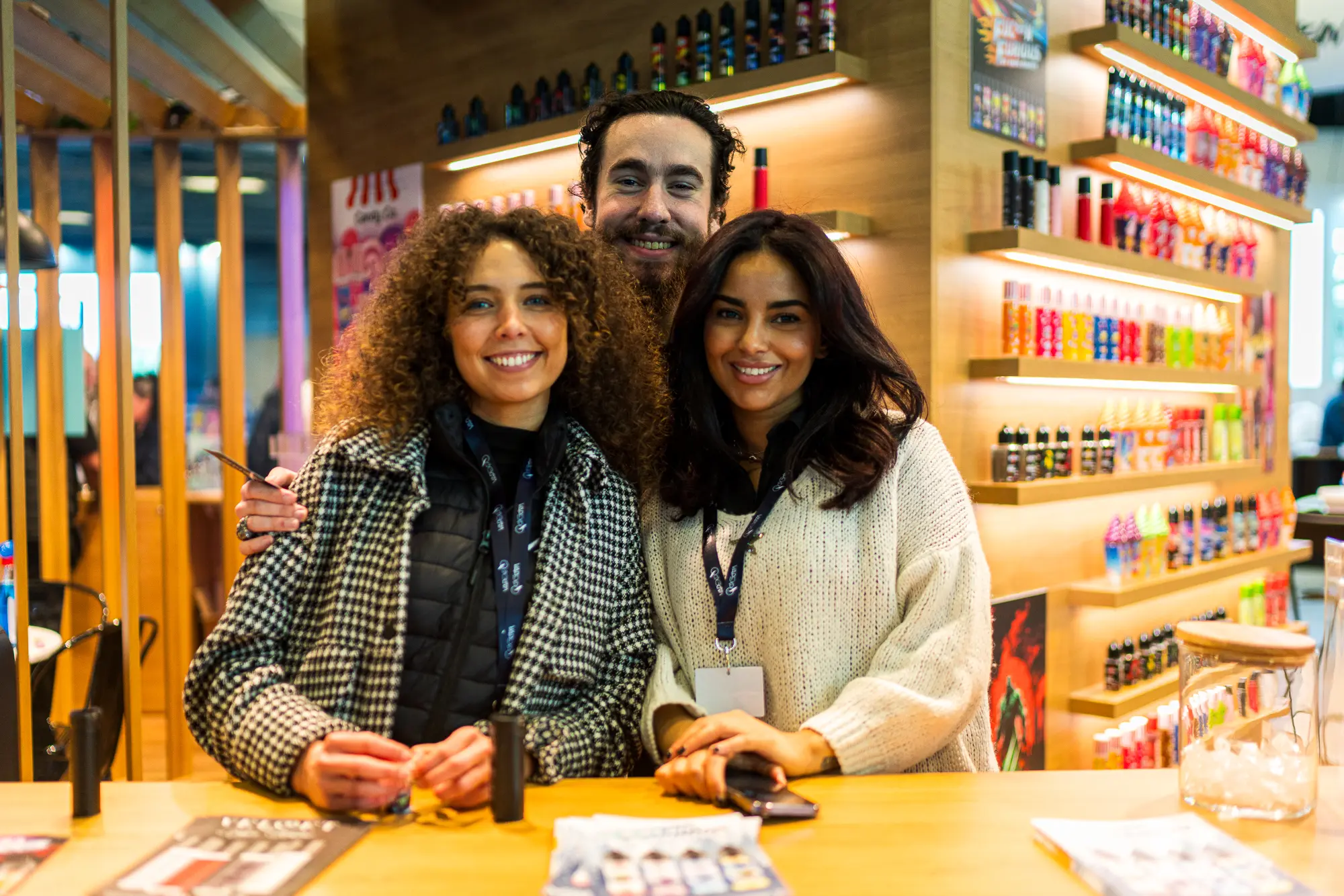 Équipe d'exposants souriants accueillant les visiteurs sur leur stand au salon Vapexpo Paris.