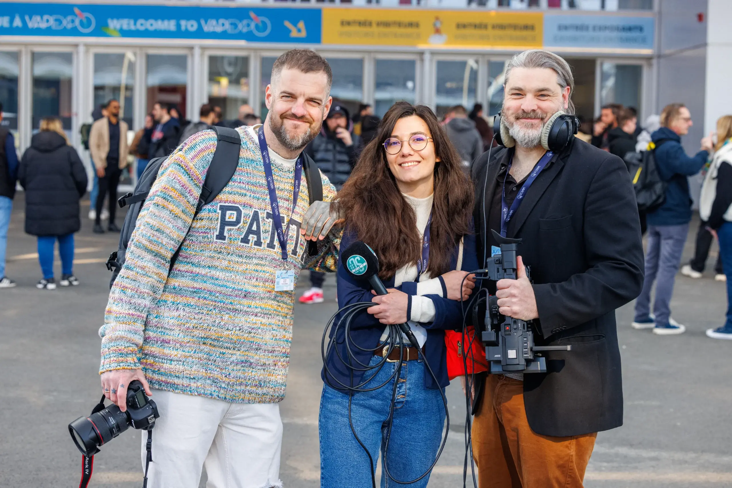 Une équipe de journalistes et photographes équipés de caméras et micros devant l'entrée du salon Vapexpo Paris