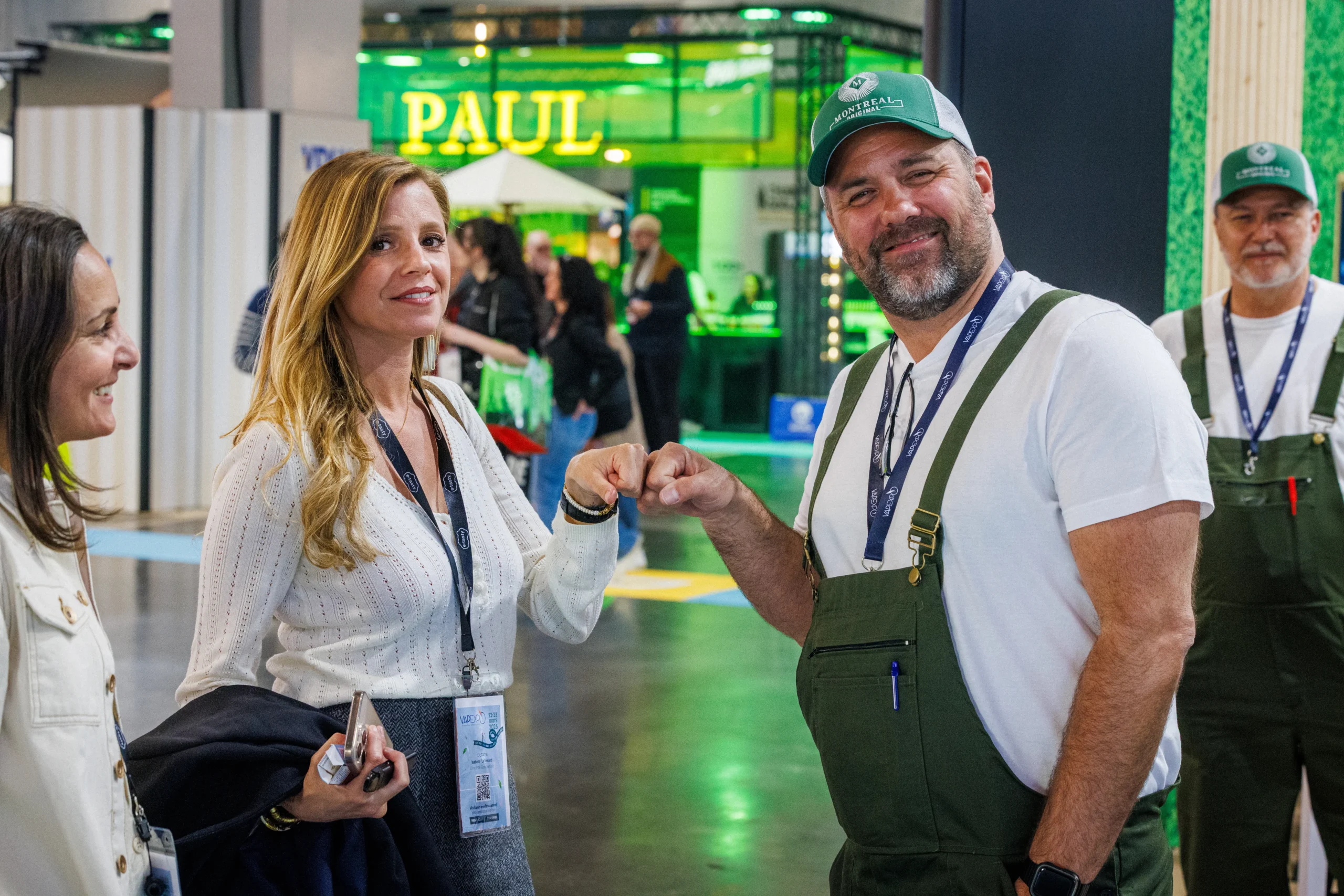 Visiteurs et exposants se saluant chaleureusement sur un stand du salon Vapexpo Paris